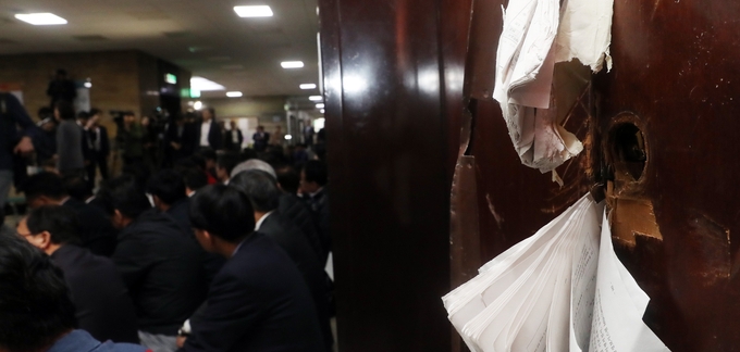 선거제 개편안과 사법제도 개혁안의 패스트트랙 지정을 놓고 여야의 극한 대치가 이어진 지난달 26일 새벽 국회 의안과 파손된 출입문 앞에서 자유한국당 의원들이 긴급 의원총회를 하고 있다. /뉴시스 