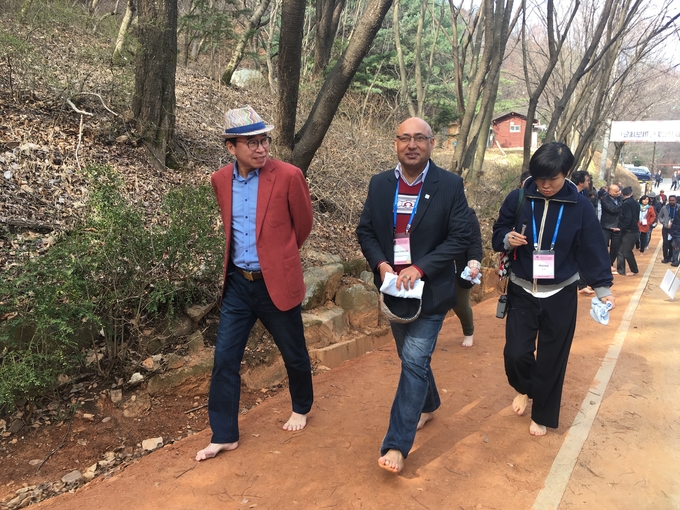 세계 기자들이 조웅래 맥키스컴퍼니 회장의 안내를 받으며 계족산 황톳길을 걷고 있다. 