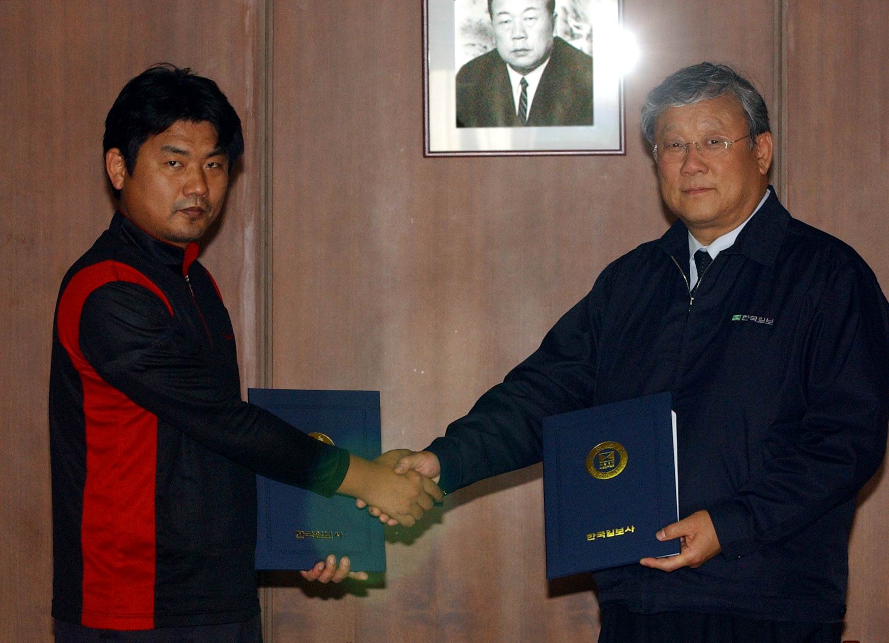 장재구 회장(右)과 전민수 위원장이 임단협안에 서명한 후 악수하고 있다.