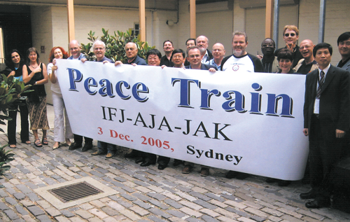 IFJ 집행위원회 이틀째 회의가 열린 3일 낮 호주 시드니 챌머스 스트리트 소재 호주기자연맹 본부 앞마당에서 크리스 워런 회장(Train의 a자 위), 이상기 회장(Peace의 끝e자 위), 에이든 화이트 사무총장(Peace의 ea 위) 및 집행위원회 위원들이 ‘Peace Train’(평화열차)?